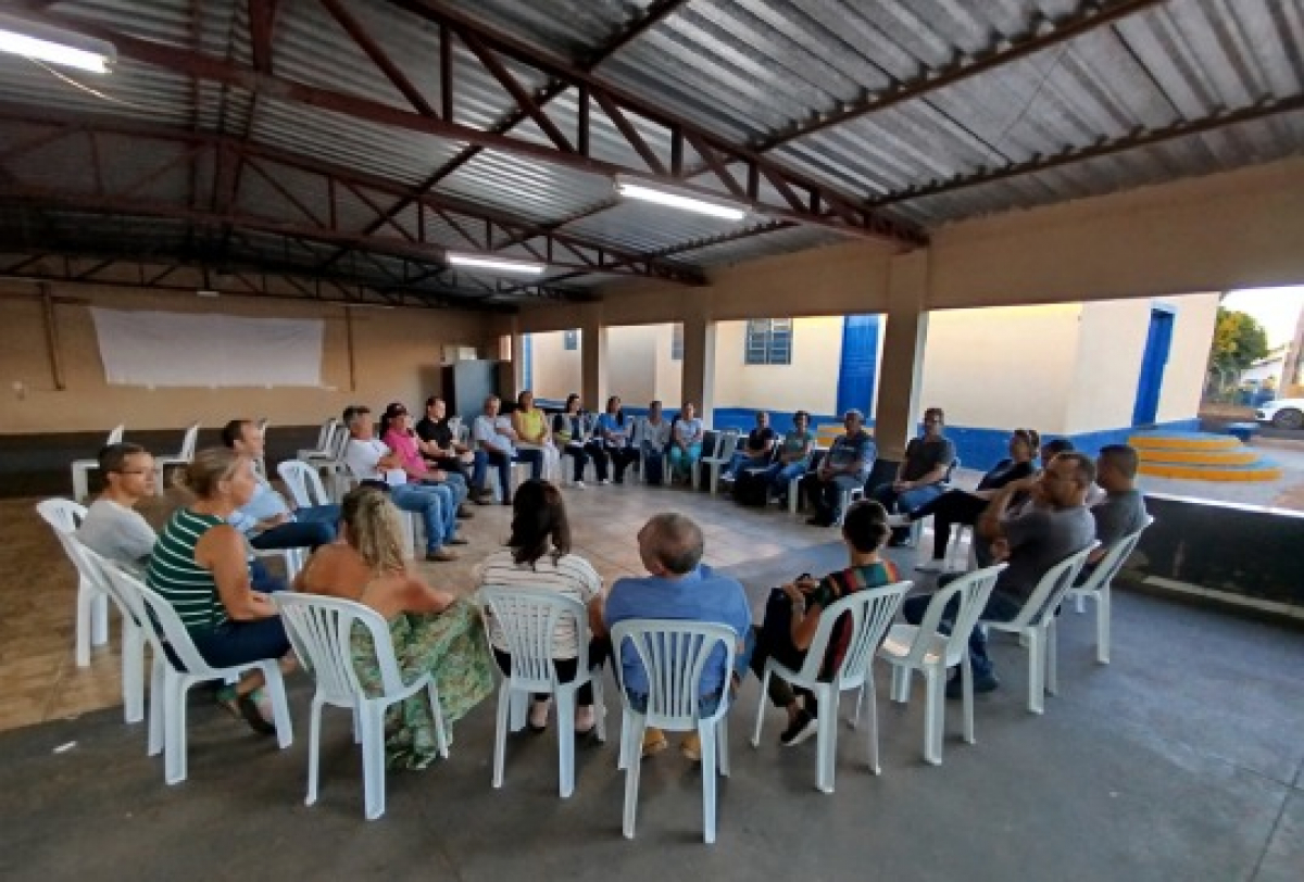 Encontro comunitário com participantes em círculo discutindo em ambiente coberto e aberto.
