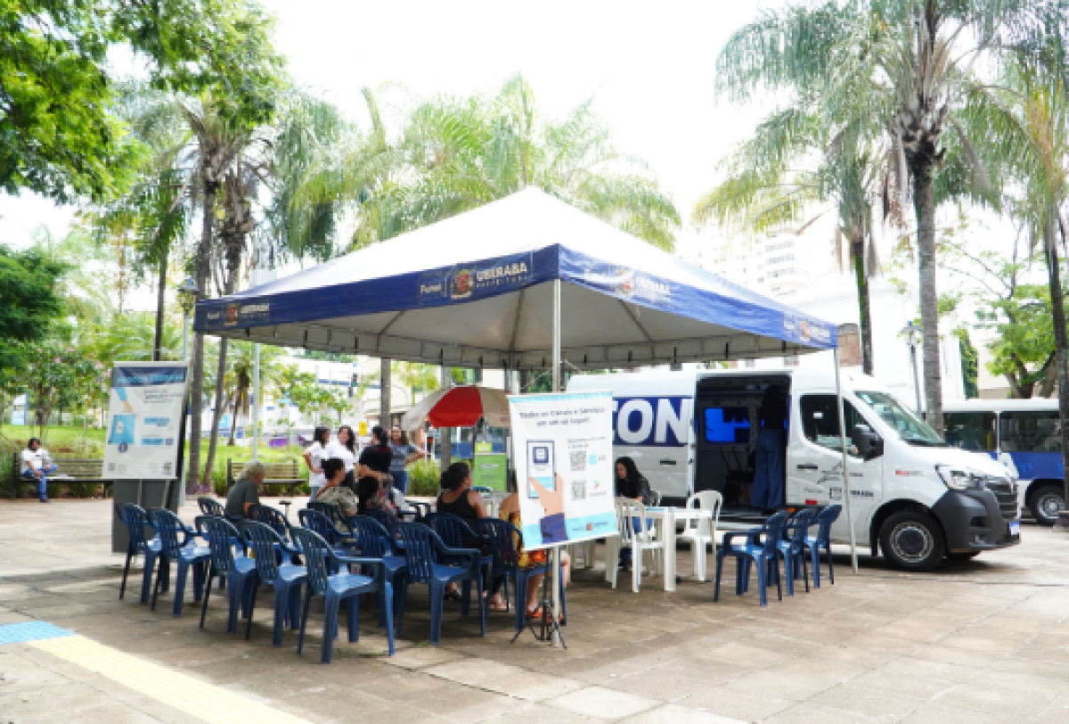 Ação itinerante da Prefeitura de Uberaba oferece atendimento ao público em tenda montada com cadeiras e van de serviços.