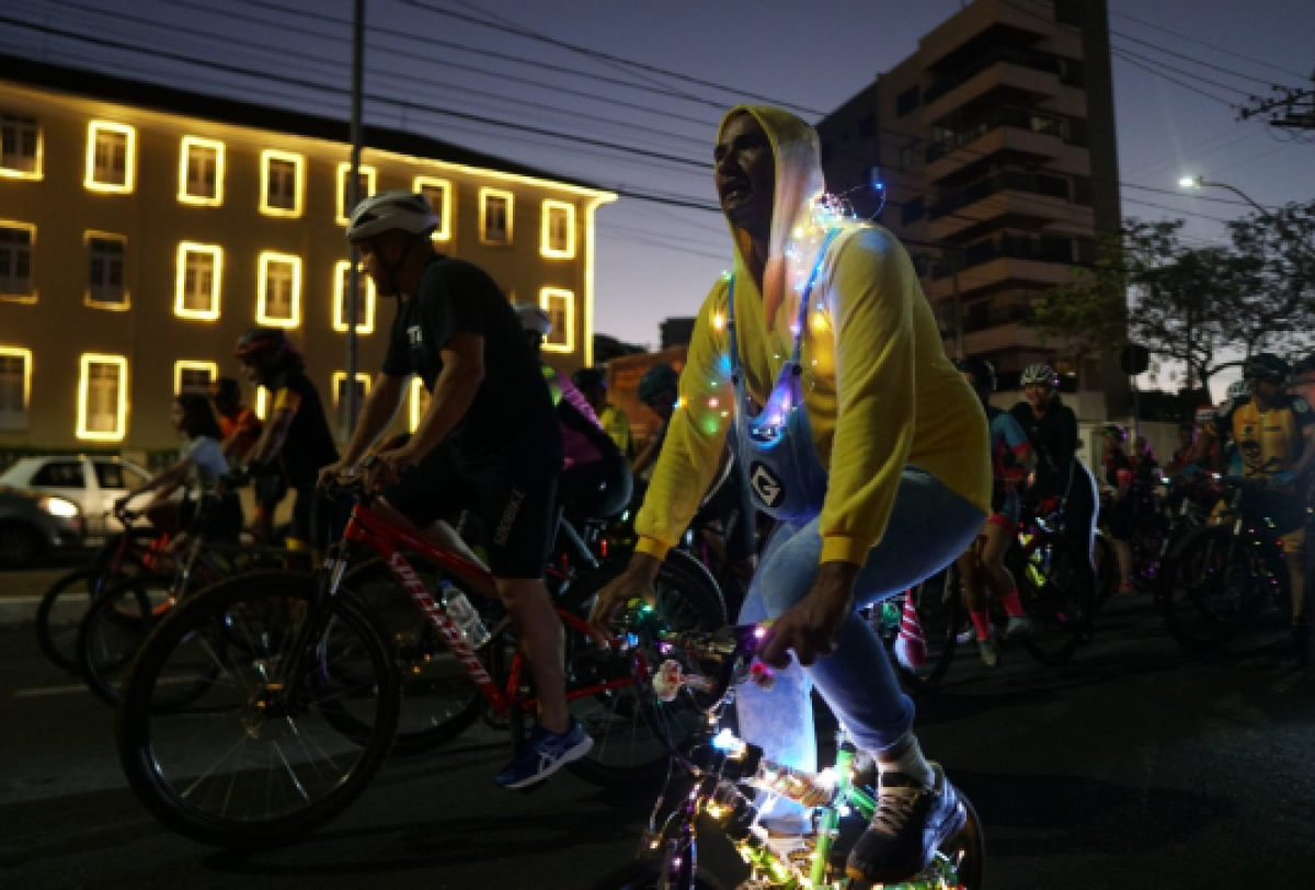 Passeio ciclístico noturno com ciclistas decorados com luzes.