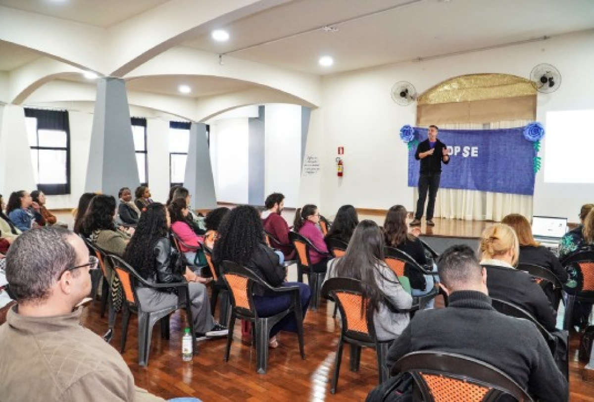 Palestra em auditório com público atento e palestrante no palco.
