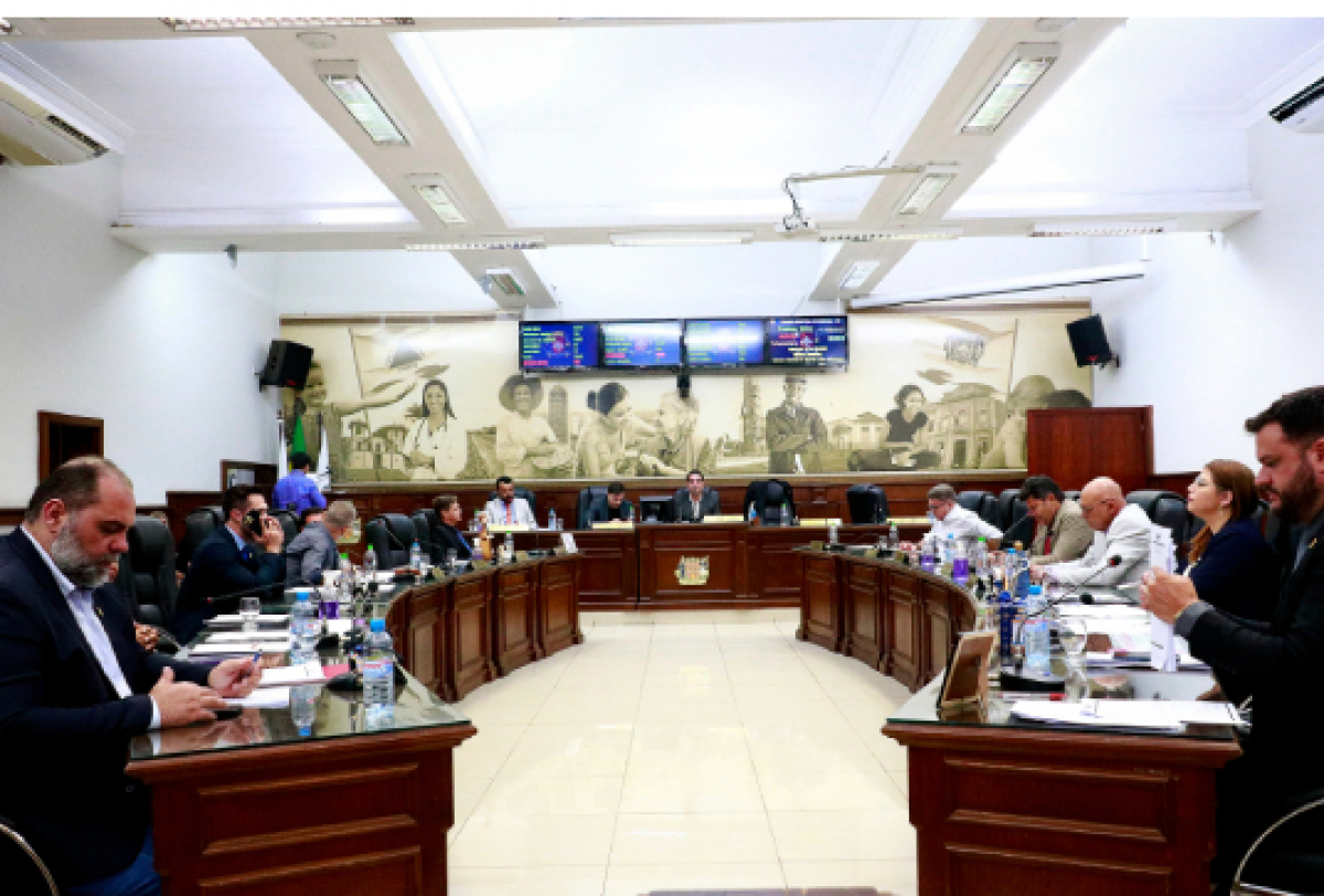 Sessão parlamentar em andamento na câmara municipal com vereadores reunidos para votações e debates. 