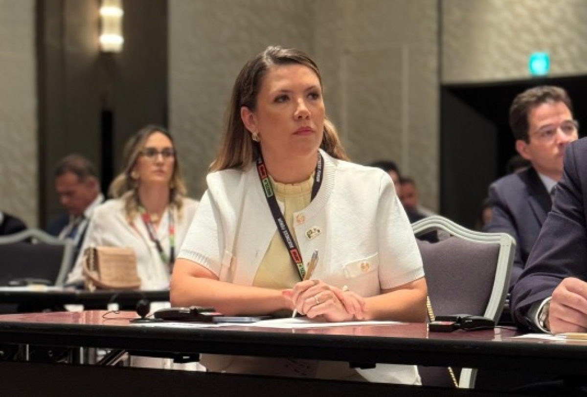Mulher participa atenta de conferência em ambiente corporativo.