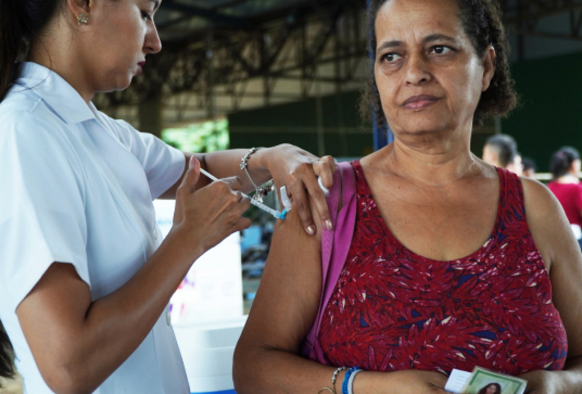 Mulher recebe vacina em campanha de imunização em ambiente comunitário.
