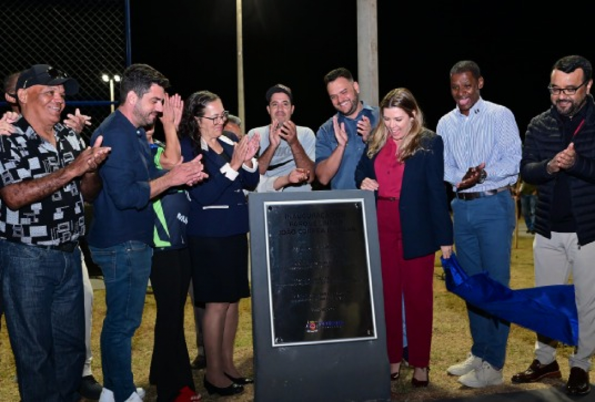 Grupo comemora a inauguração de obra pública com placa descerrada em evento noturno.