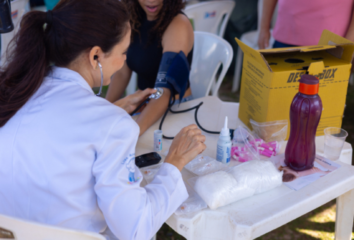 Profissional de saúde realizando aferição de pressão arterial em uma paciente em ambiente comunitário.