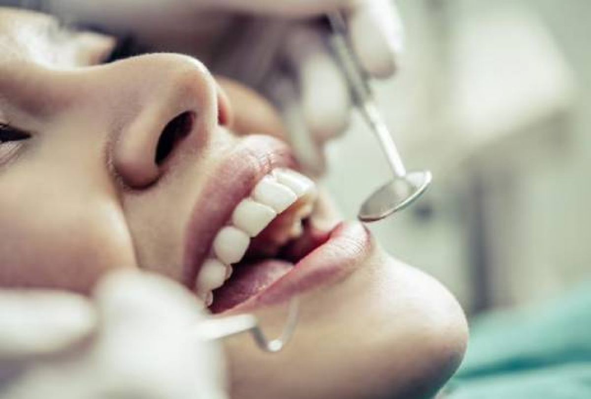 Imagem mostrando um tratamento dentário com uso de um espelho para verificar dentes ou gengivas.