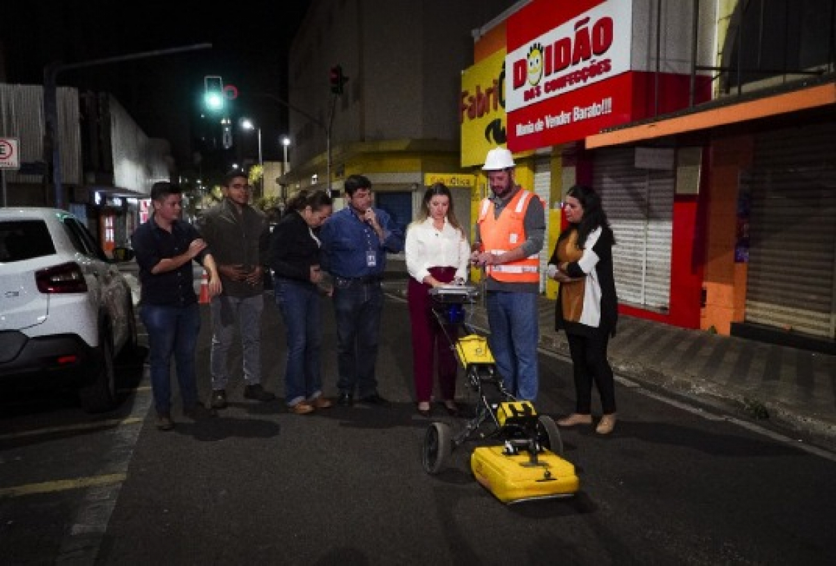 Equipe técnica acompanha inspeção noturna com equipamento de análise em via urbana.