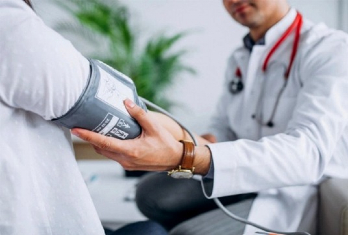 Imagem de um médico medindo a pressão arterial de um paciente com um esfigmomanômetro.