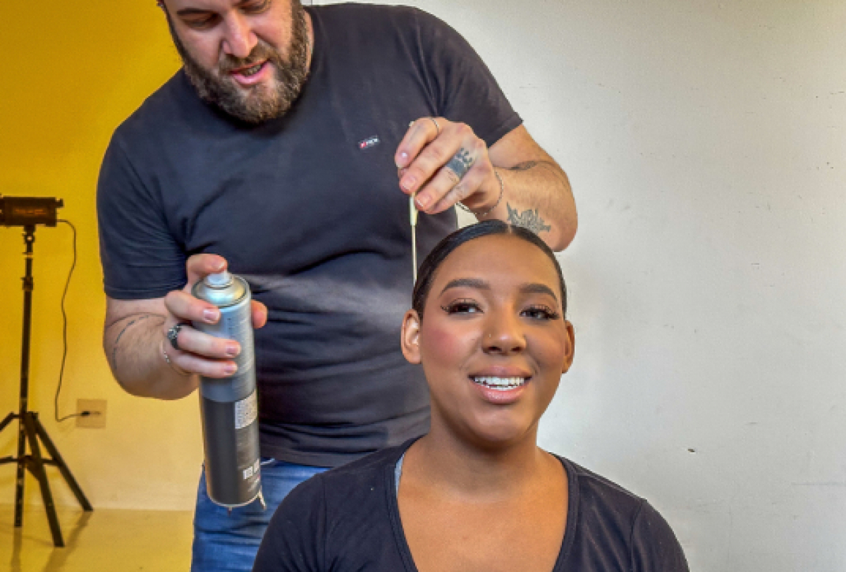 Um cabeleireiro estilizado o cabelo de uma cliente usando spray fixador.