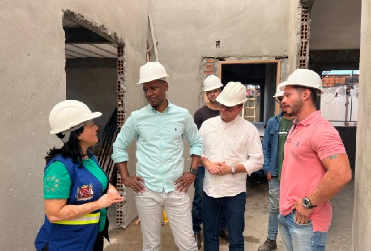 Grupo com capacetes realiza vistoria em obra em andamento.