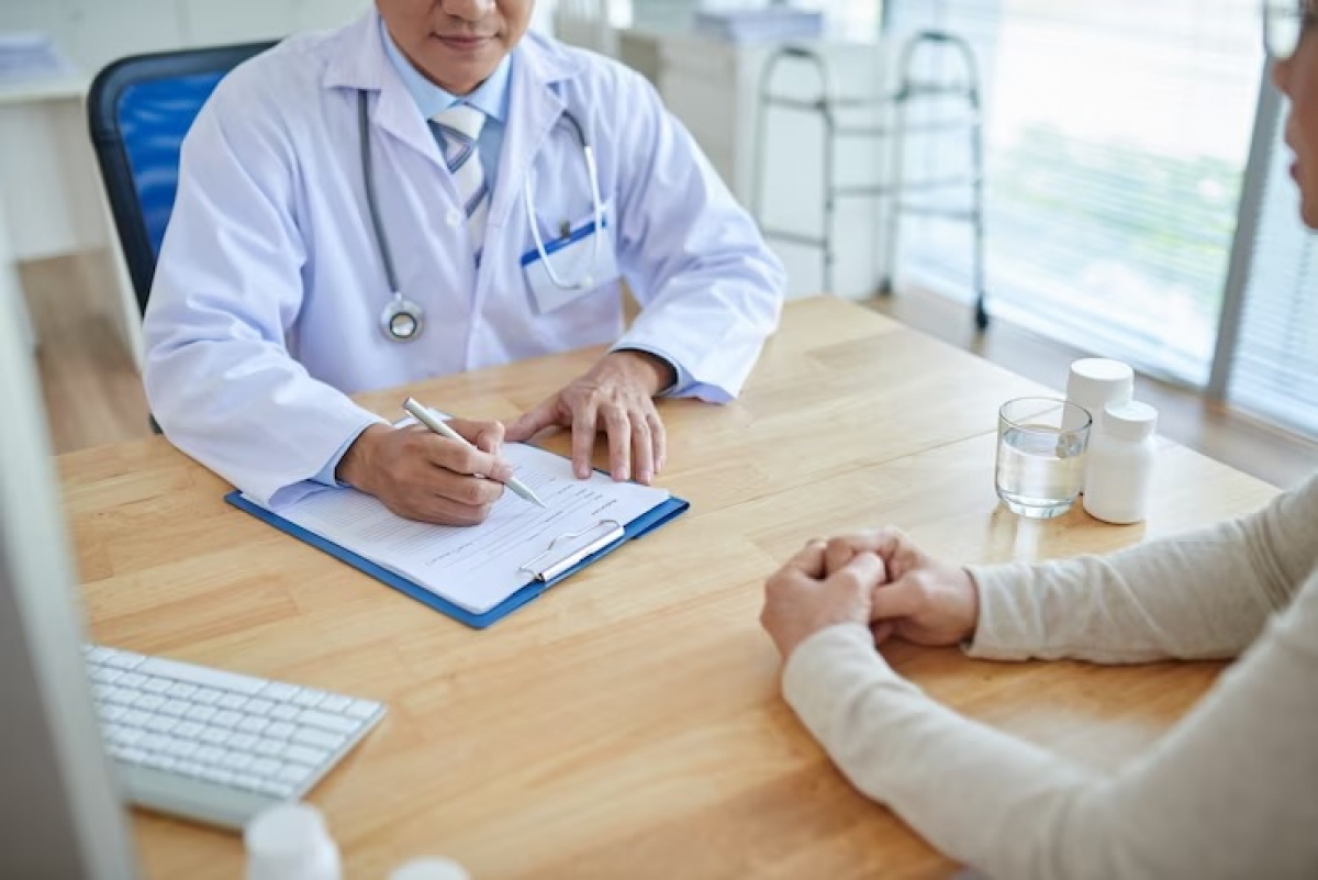 Um médico consulta um paciente em um consultório, fazendo anotações em uma prancheta.