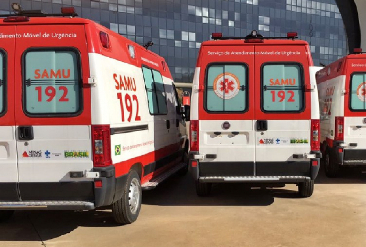 A imagem mostra três ambulâncias SAMU 192 estacionadas lado a lado em frente a um prédio moderno com janelas refletivas.