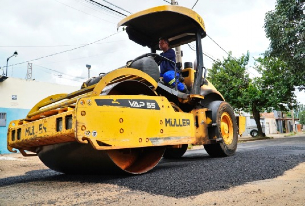 Máquina compactadora trabalha na pavimentação de uma rua com asfalto novo.