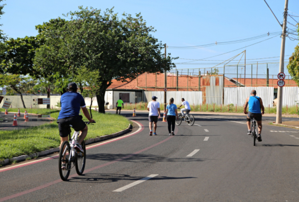 Pessoas caminhando e pedalando em uma pista recreativa ao ar livre.