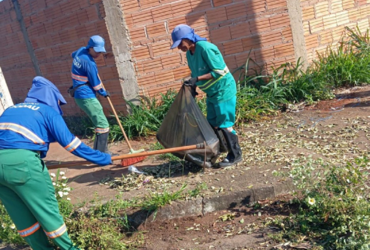 <p>A imagem mostra três indivíduos limpando uma rua com vassouras e sacos de lixo. </p>