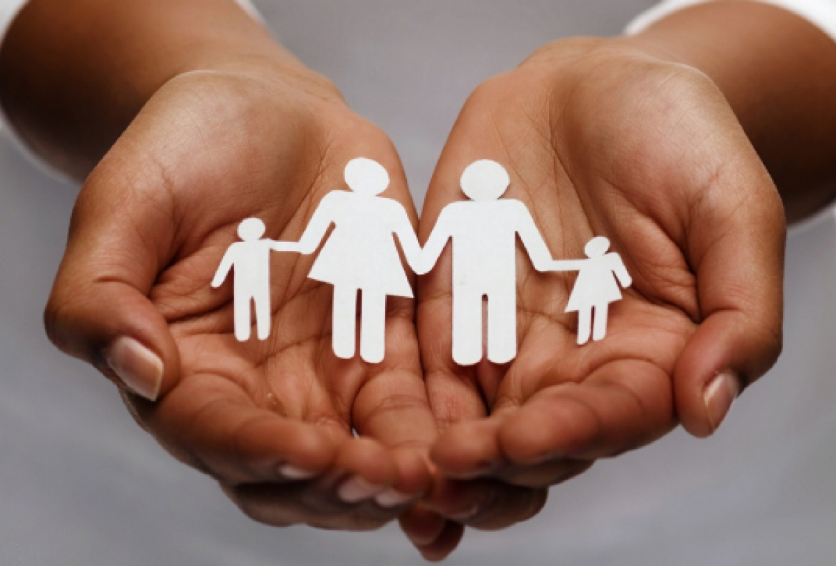 Imagem simboliza proteção e cuidado familiar, com mãos segurando recortes de papel representando uma família.