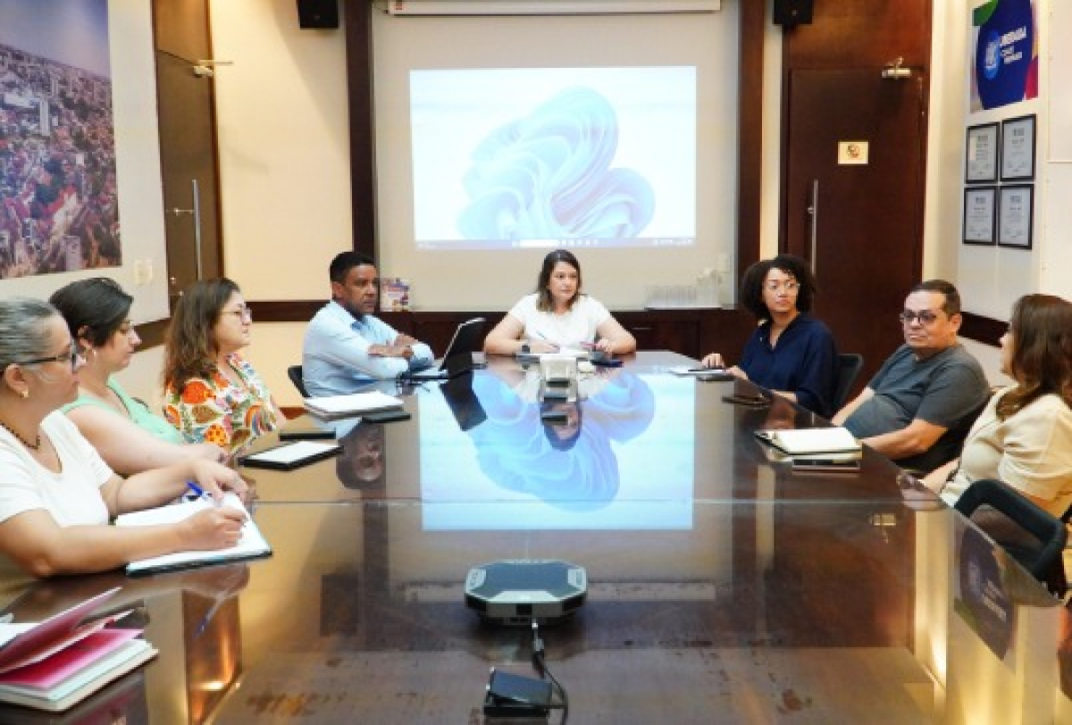 Reunião formal com equipe diversa discutindo assuntos organizacionais em ambiente corporativo.