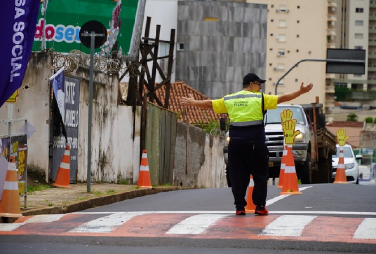 Um agente de trânsito orienta os veículos a parar em uma faixa de pedestres, garantindo a segurança no trânsito em uma área urbana