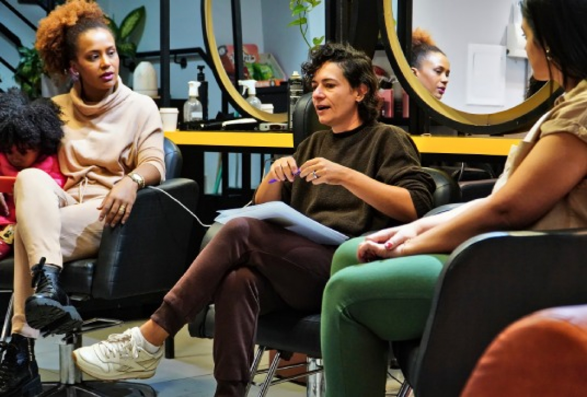 Mulheres participam de uma conversa em grupo em um ambiente de salão de beleza.