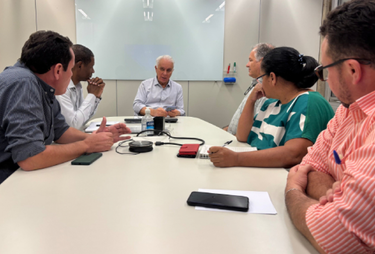 Reunião de trabalho com equipe técnica discutindo projetos em sala corporativa. 