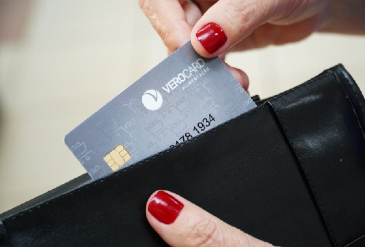 Pessoa retira ou guarda um cartão VeroCard de uma carteira preta.