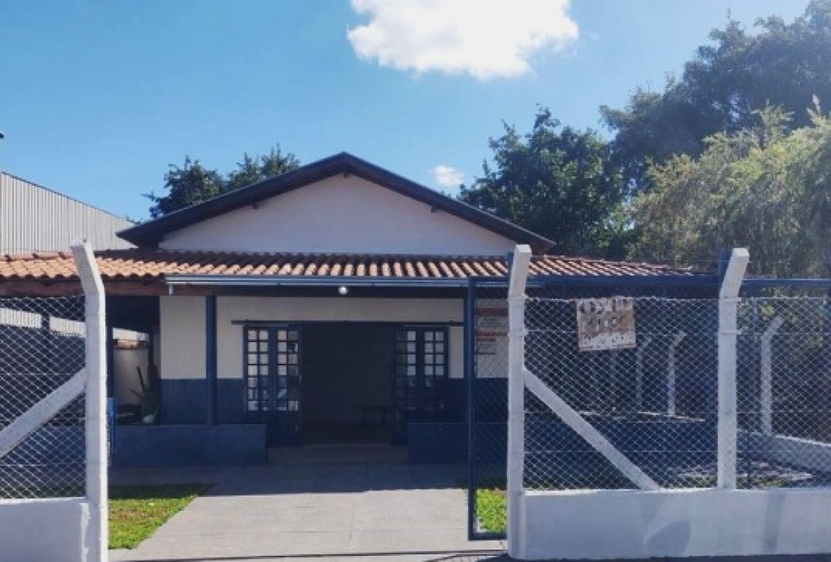 Casa térrea cercada por grade metálica, localizada em área urbana e ensolarada.