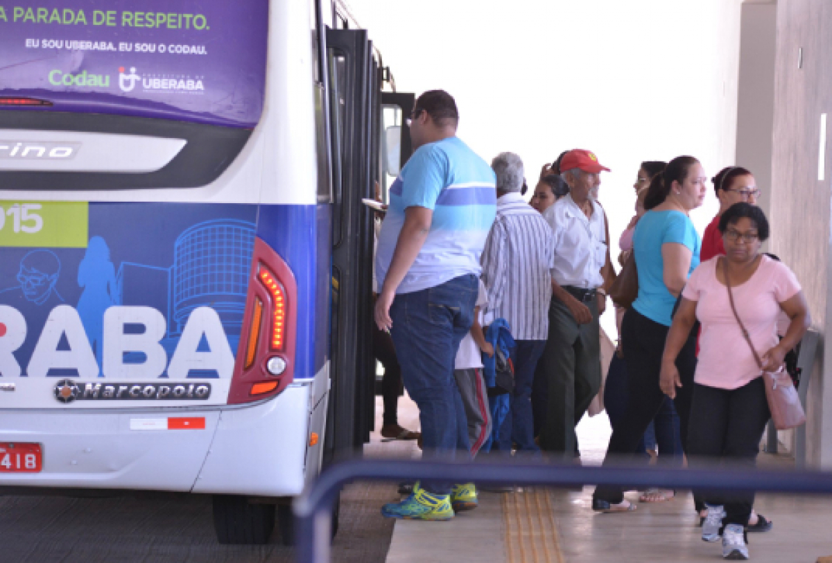 Passageiros embarcando em um ônibus em um terminal urbano.