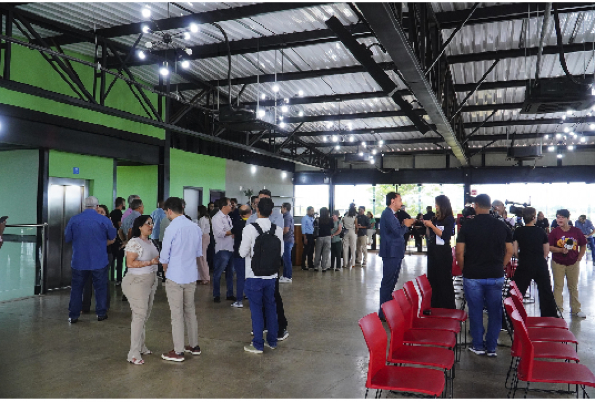 Pessoas reunidas em um evento em um galpão amplo e iluminado.