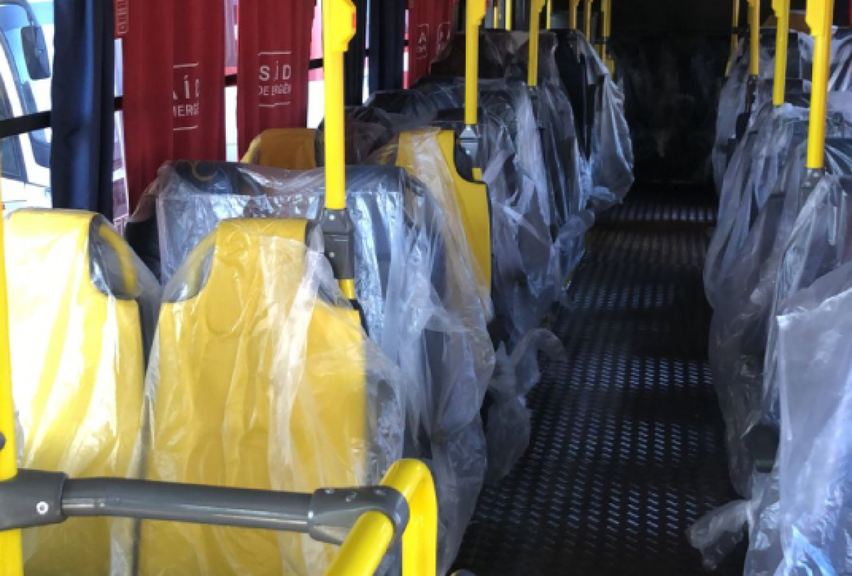 Interior de ônibus novo com assentos plastificados e cortinas vermelhas personalizadas. 