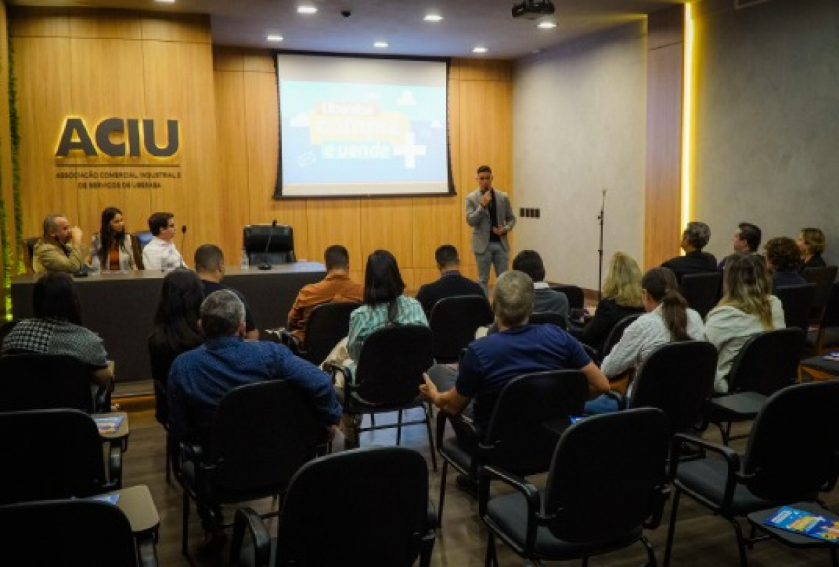 Palestra é realizada na sede da ACIU com público atento e apresentação projetada na tela.