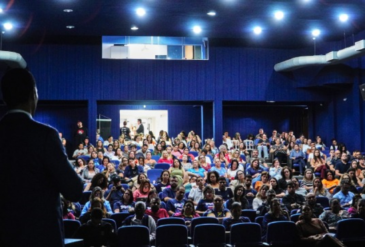 Auditório lotado com público atento assistindo a uma palestra ou apresentação.