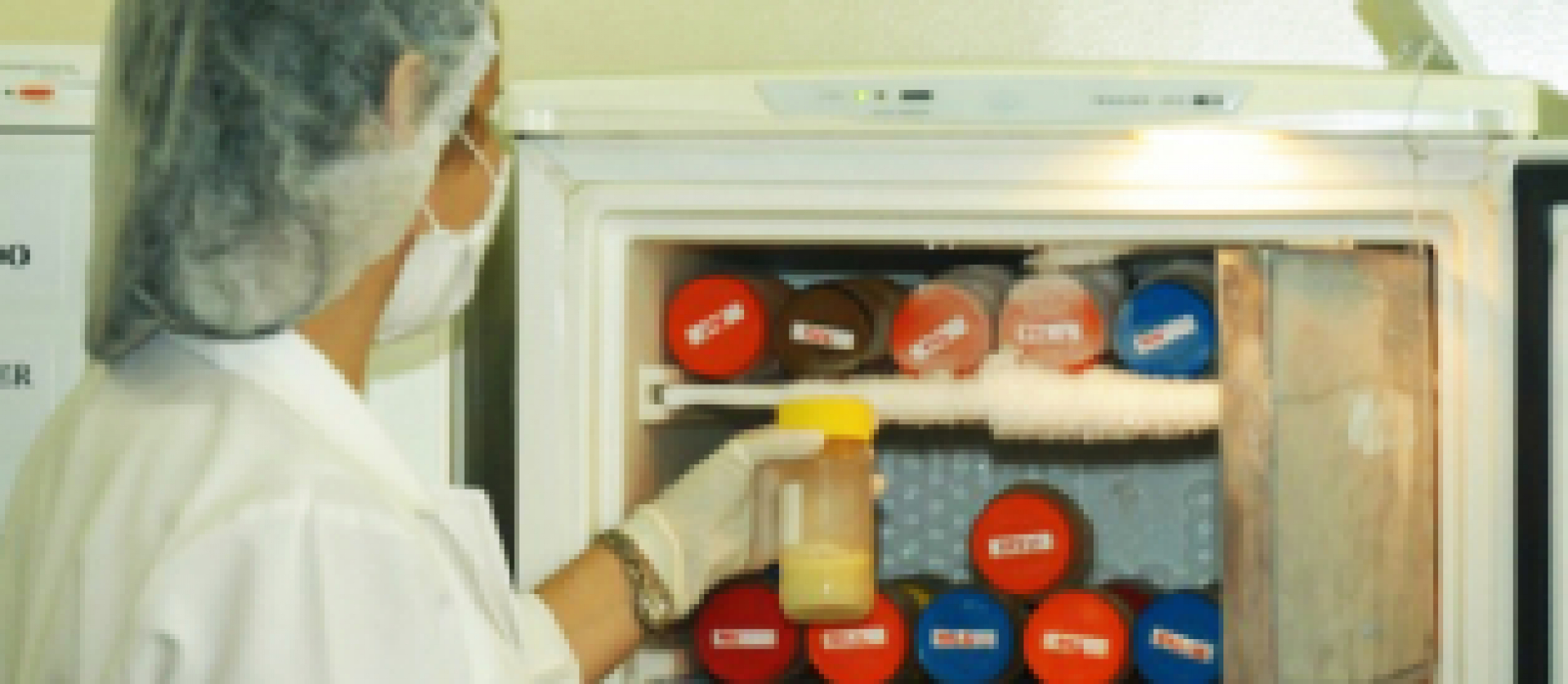 Profissional manuseia leite materno pasteurizado em um banco de leite humano, pronto para distribuição.