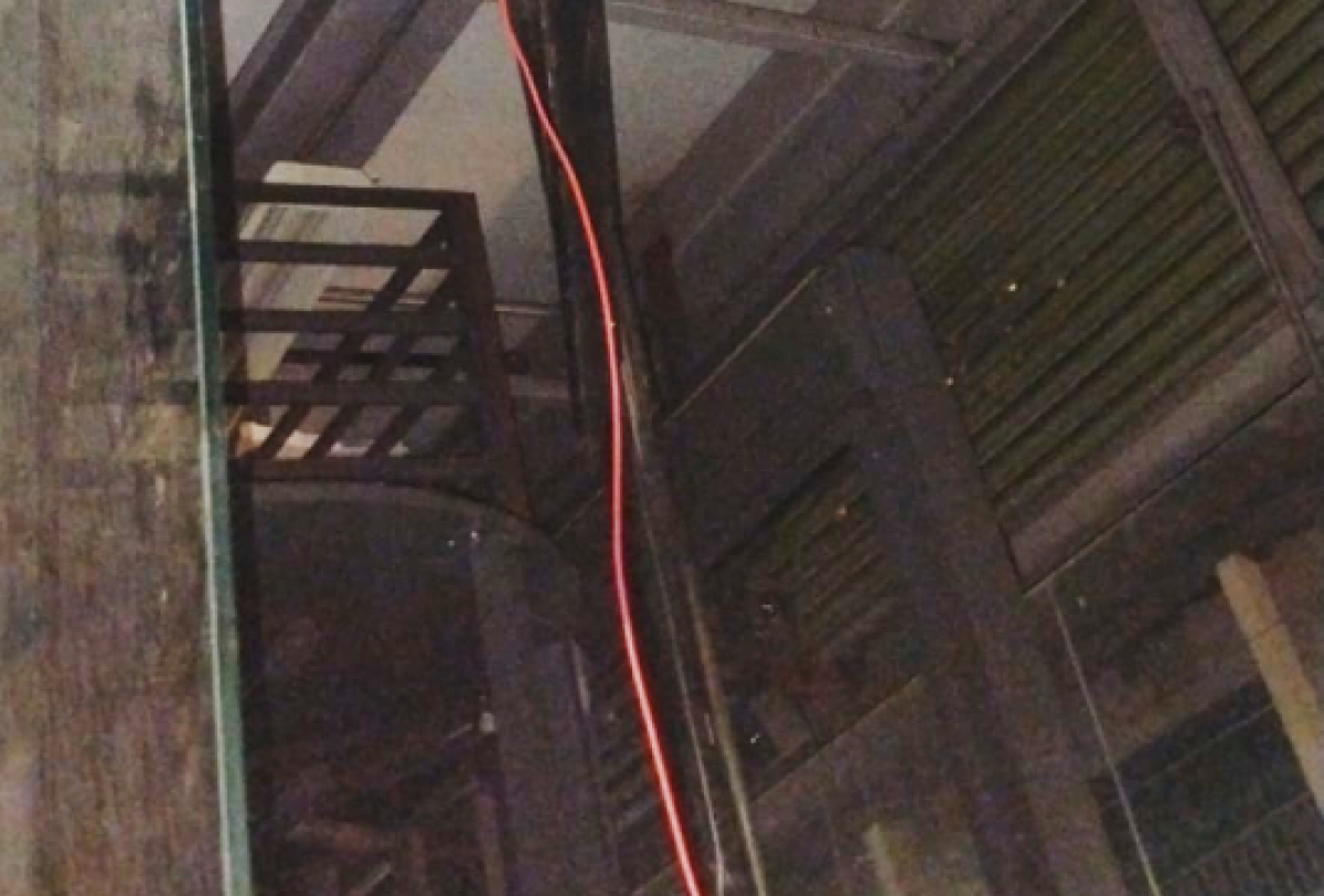 Estrutura interna com vidro, cabos expostos e grades metálicas em ambiente industrial ou em reforma.