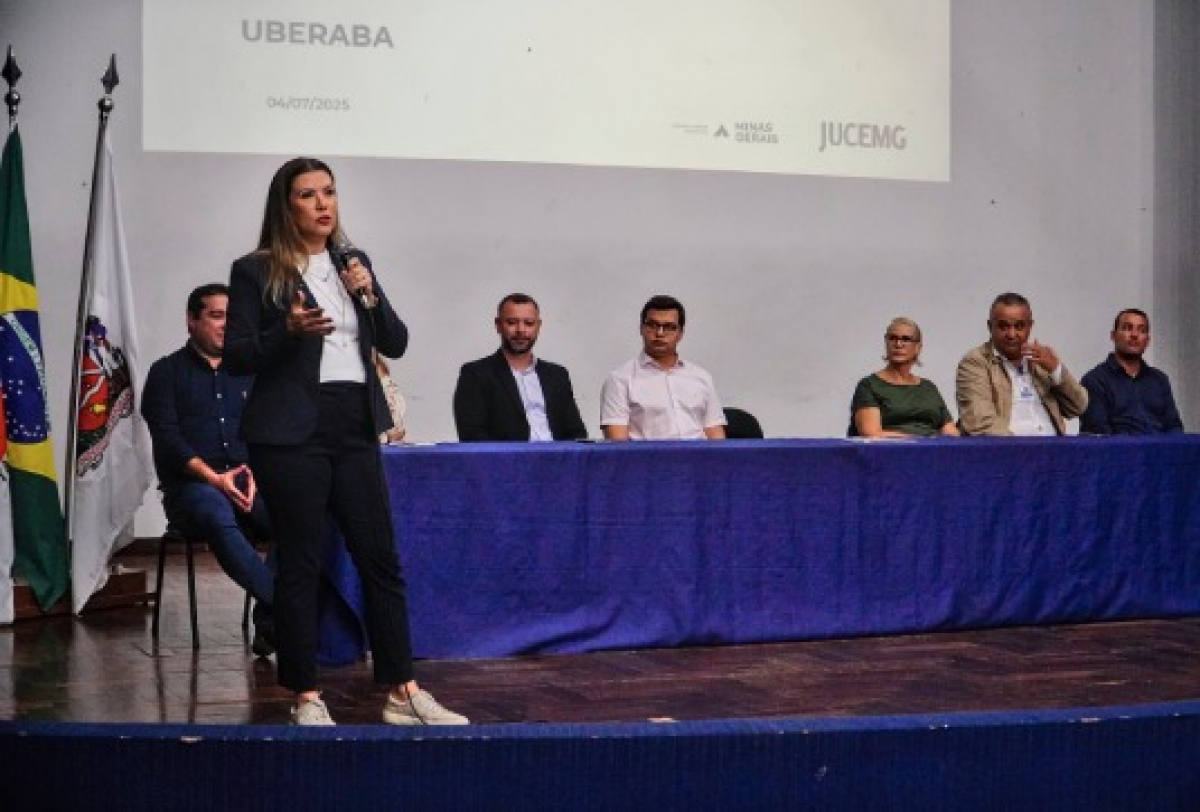 Evento institucional em Uberaba com apresentação da JUCEMG e presença de autoridades no palco. 