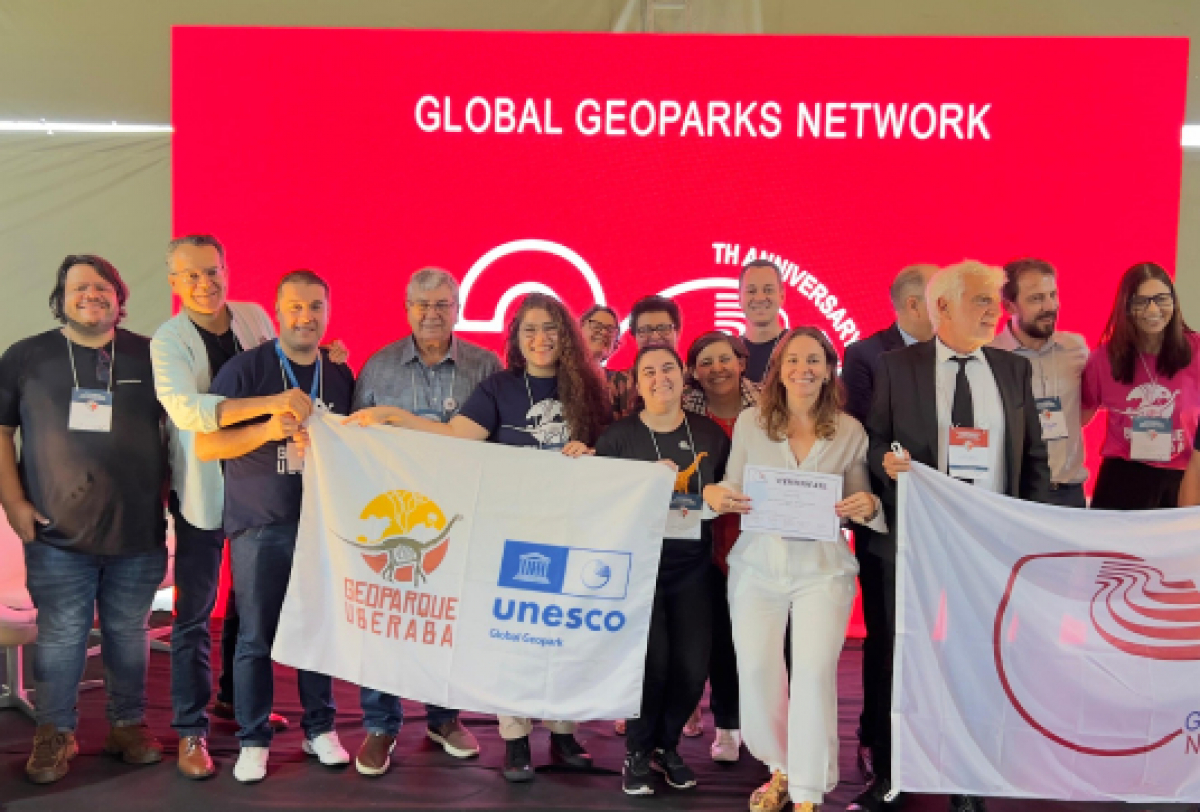 A imagem mostra um grupo de pessoas em um palco com banners GEOPARQUE UBERABA e GLOBAL GEOPARKS NETWORK.