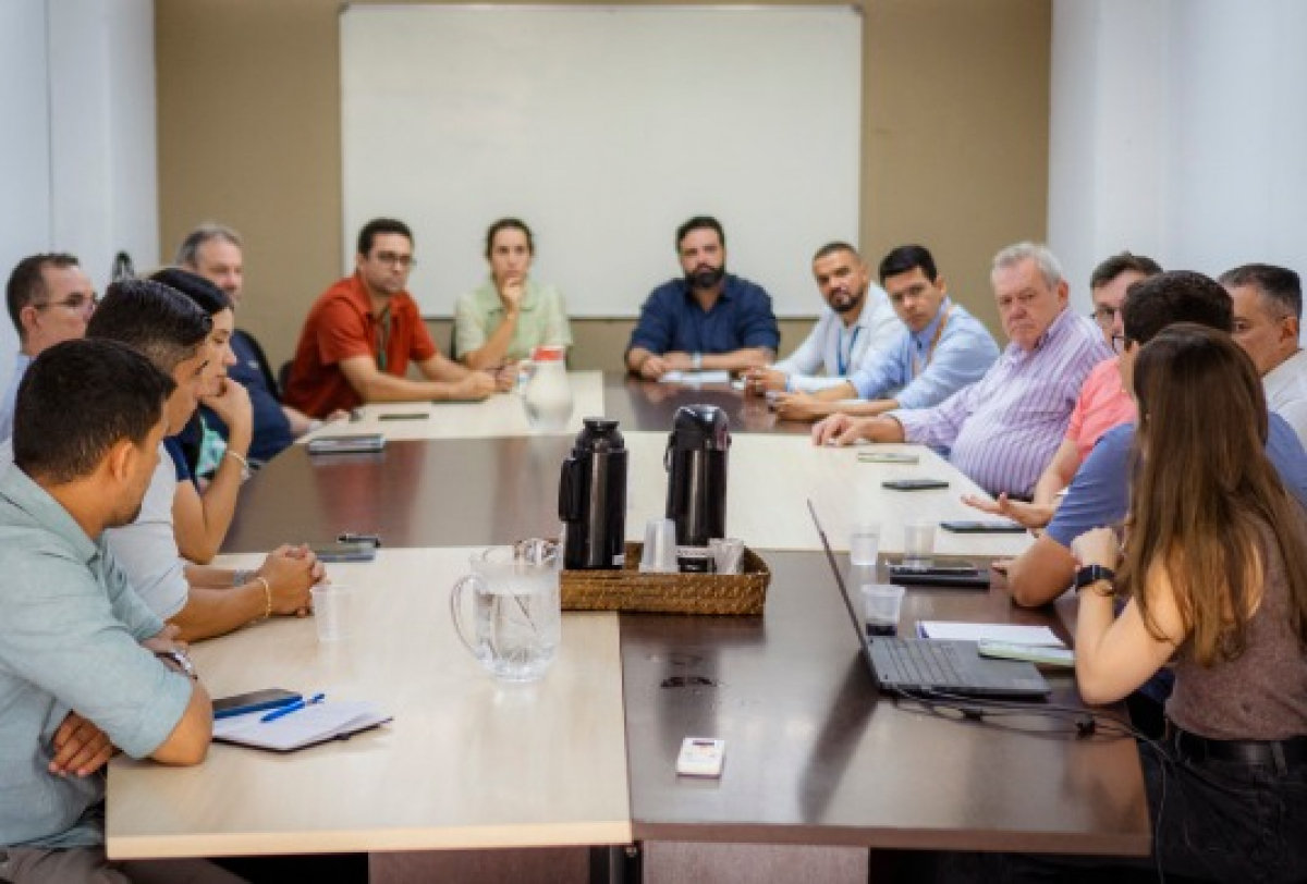 Reunião formal com diversos participantes discutindo temas possivelmente institucionais ou administrativos.