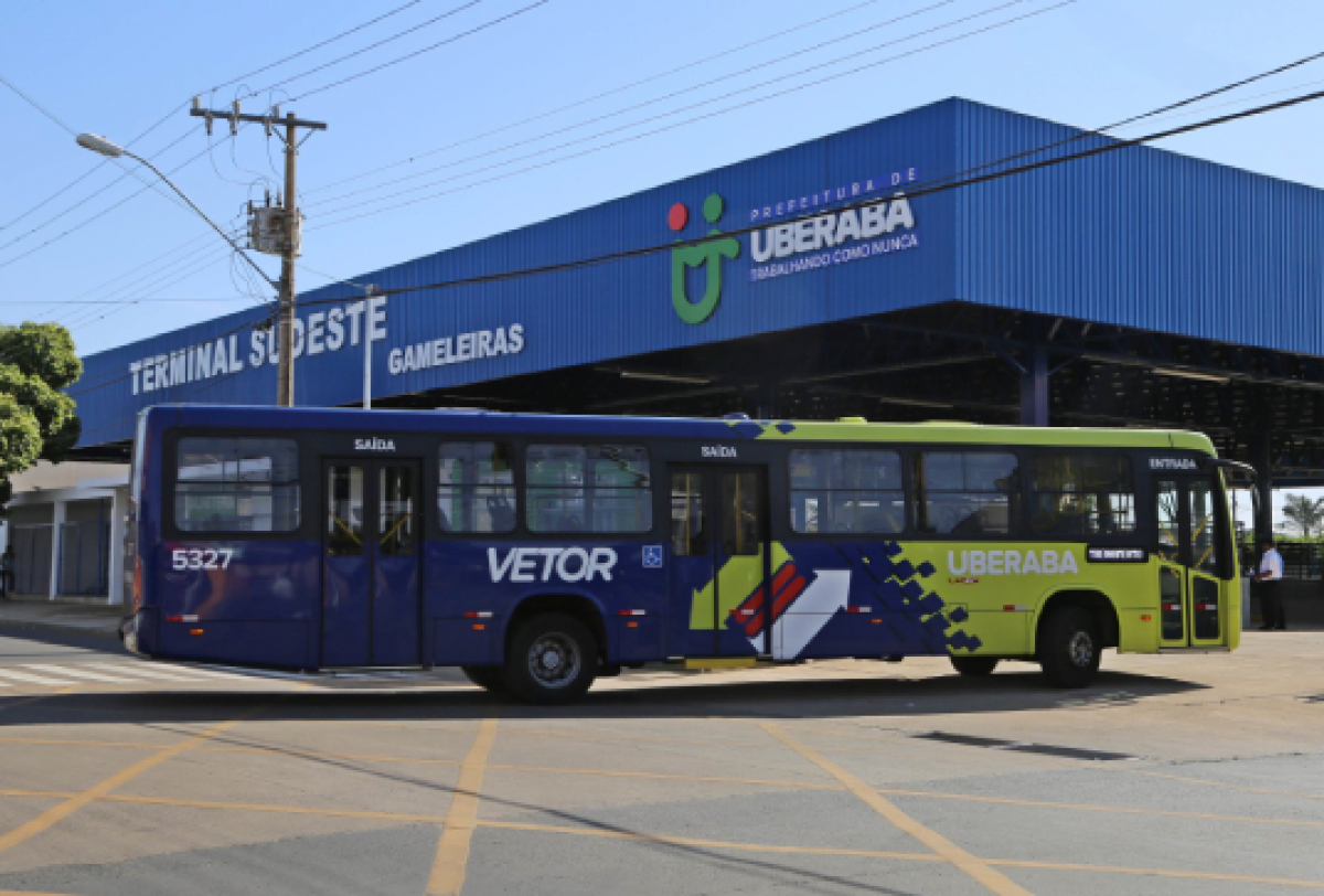A imagem mostra um ônibus de transporte público na frente de um terminal de ônibus em Uberaba.