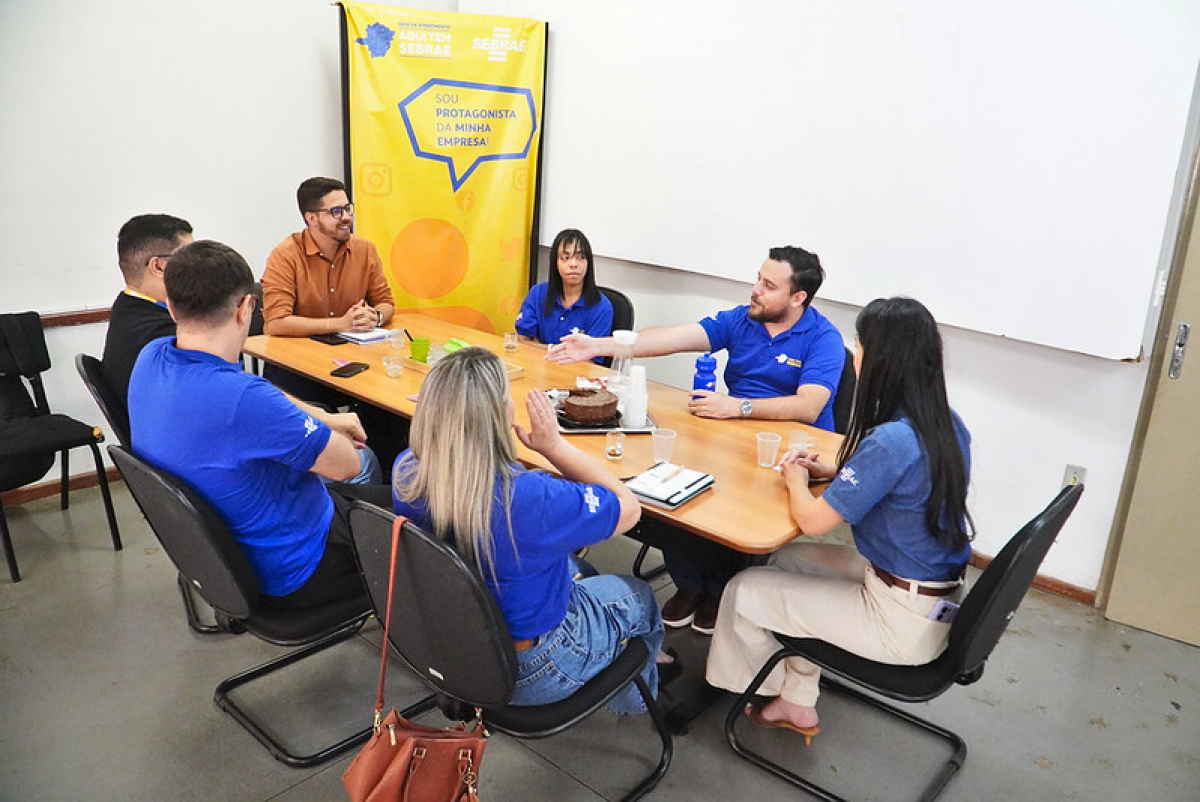 Participantes do programa Jovem Empreendedor do Sebrae se reúnem em uma mesa para dialogar e compartilhar ideias.