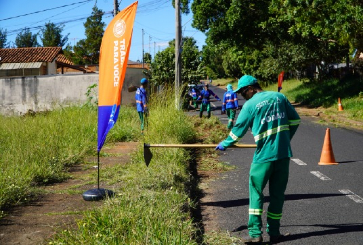 Servidores realizam roçada e limpeza da vegetação em área pública para manutenção urbana.