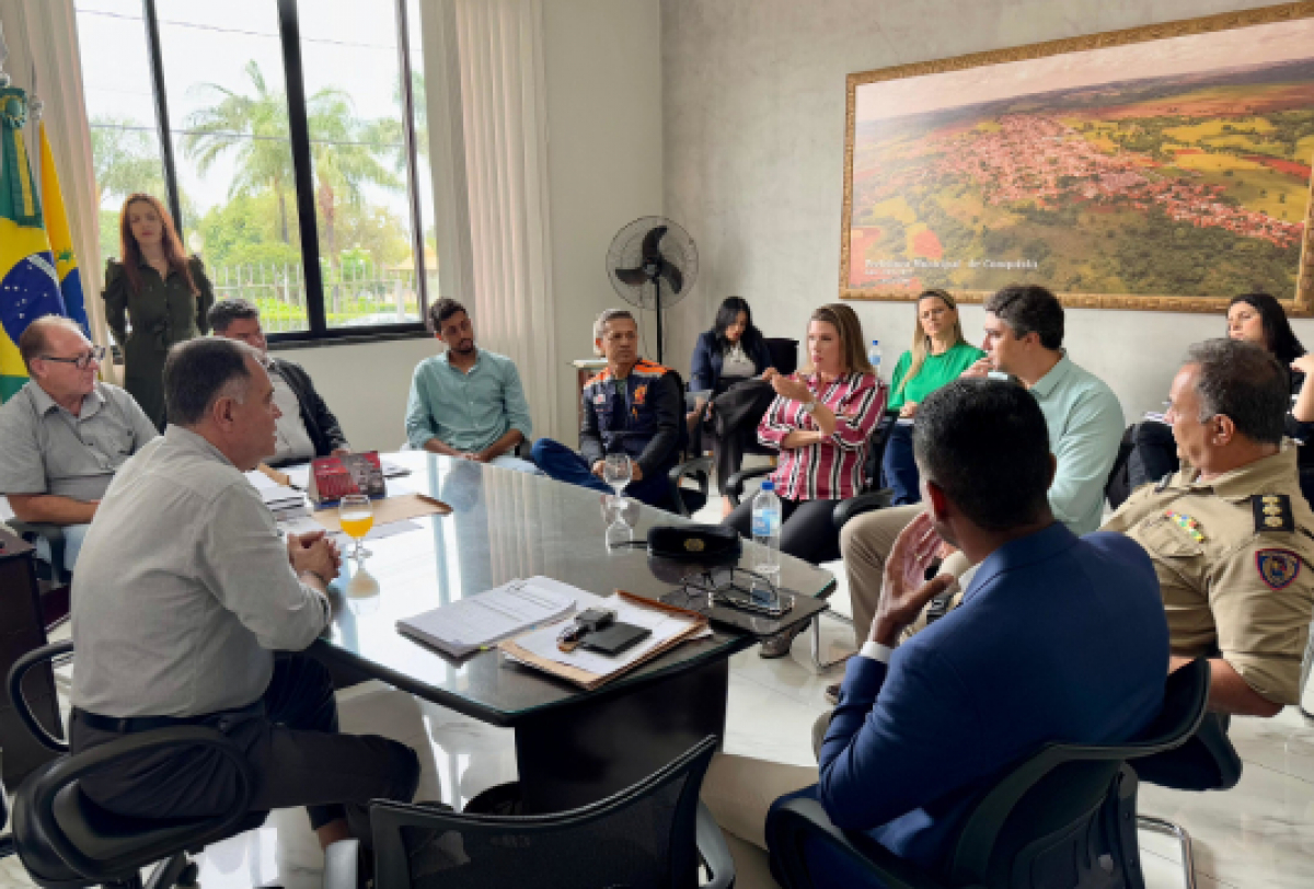 Reunião formal entre autoridades municipais e forças de segurança em um gabinete.