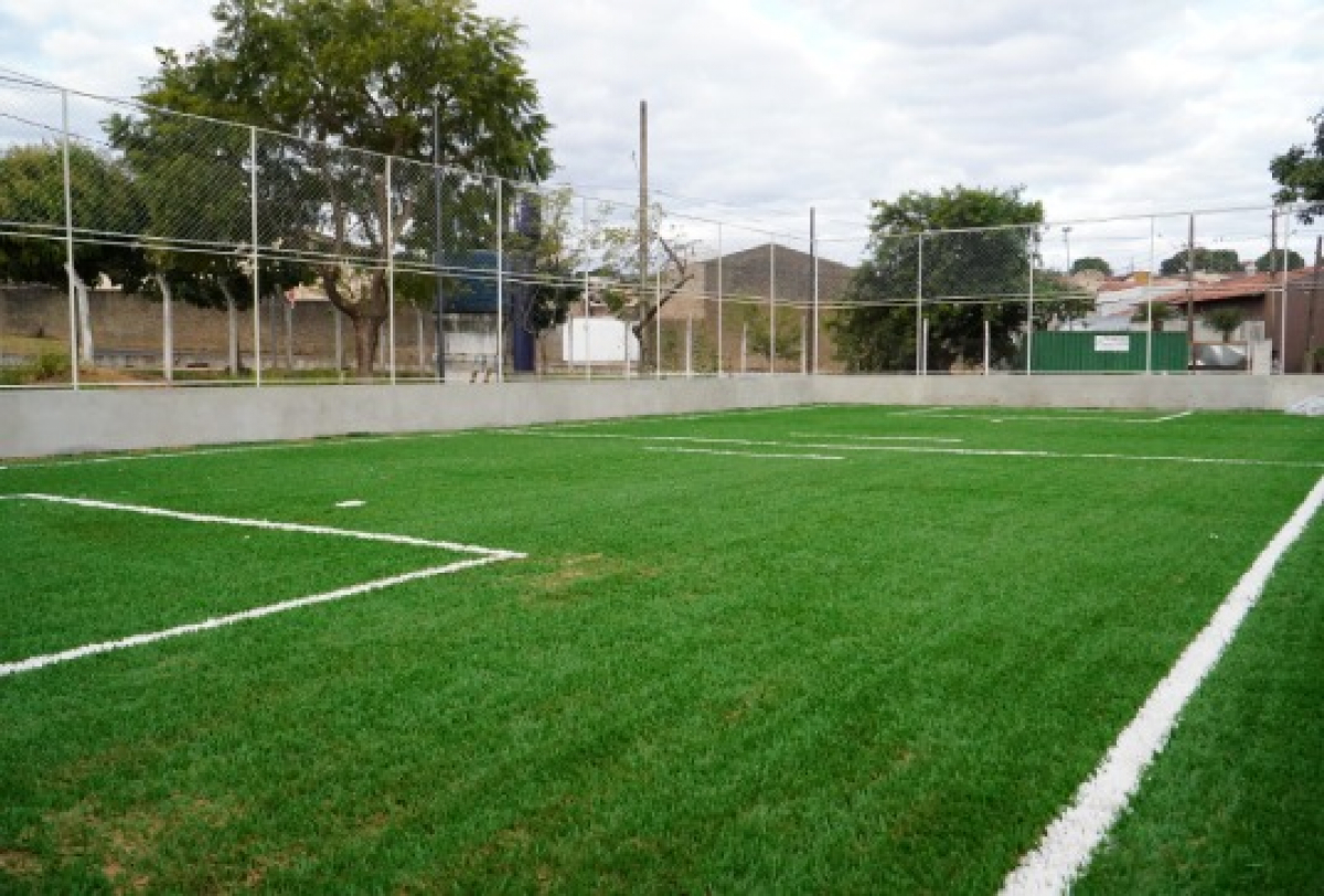 Quadra esportiva revitalizada com novo gramado sintético em área urbana.