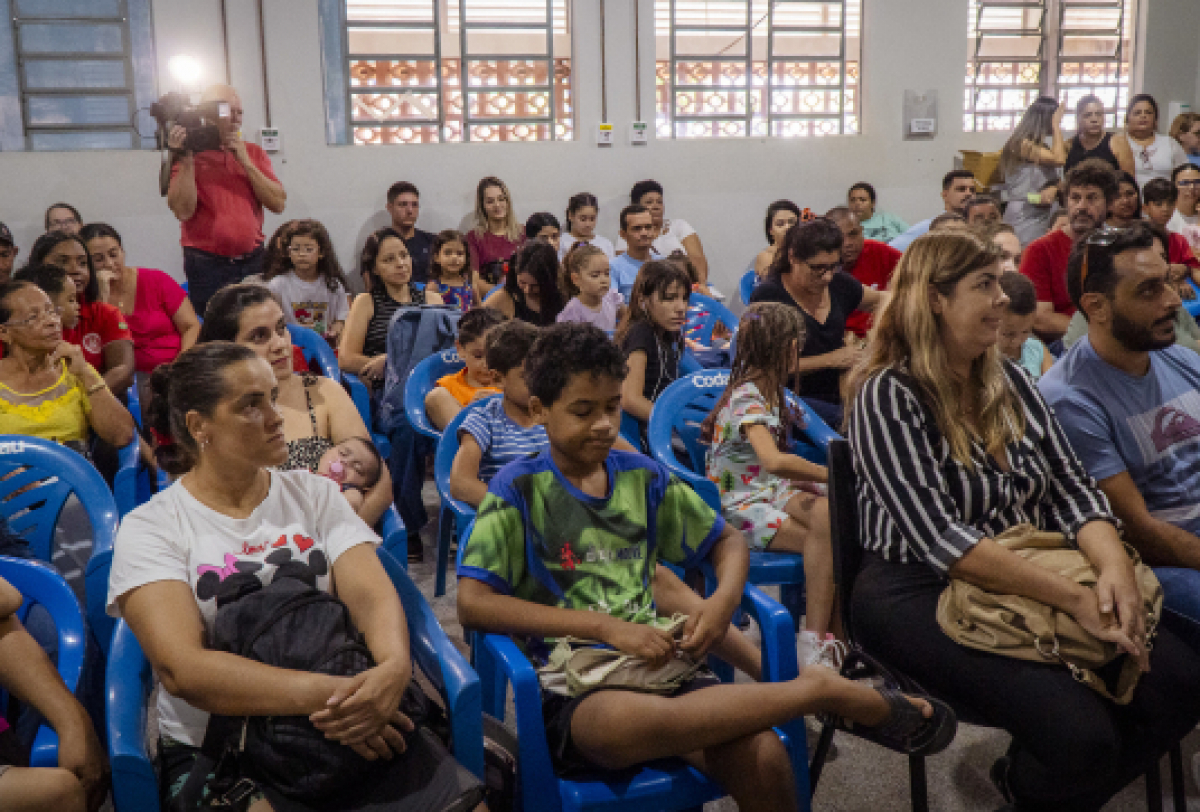 Um grupo de adultos e crianças participa de um evento.