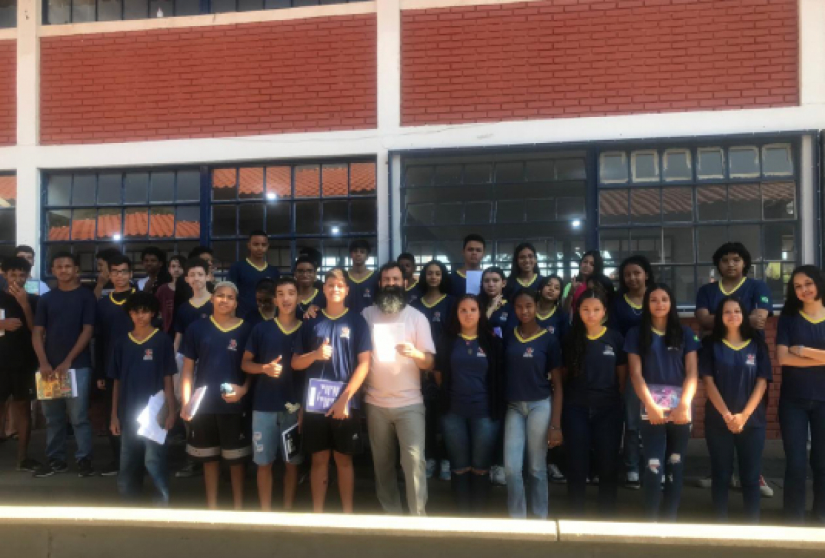 Grupo de estudantes em uniforme escolar posando para foto em frente a um prédio.