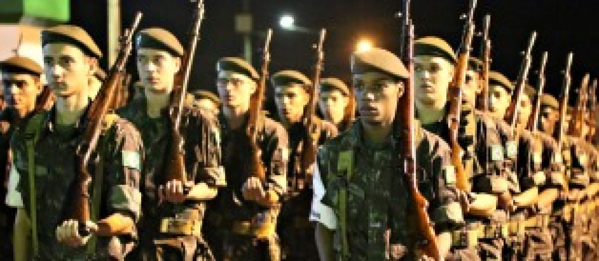 Soldados em uniformes camuflados participam de um treinamento ou cerimônia em formação.