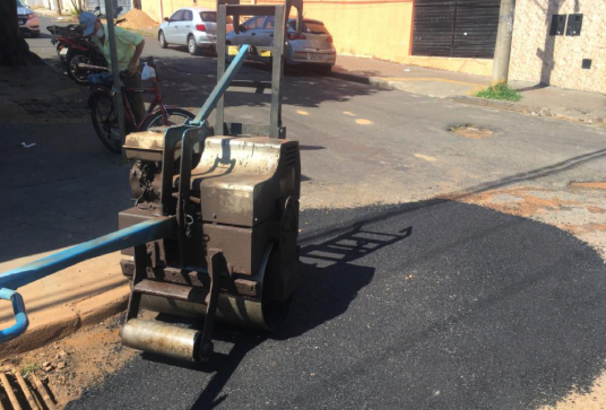 Máquina realiza serviço de tapa-buracos para melhorar pavimentação de rua.