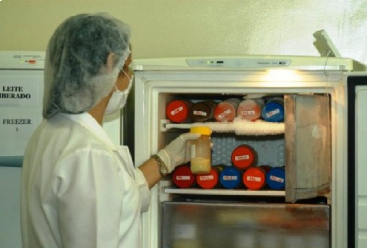 Profissional manuseia leite materno pasteurizado em um banco de leite humano, pronto para distribuição.