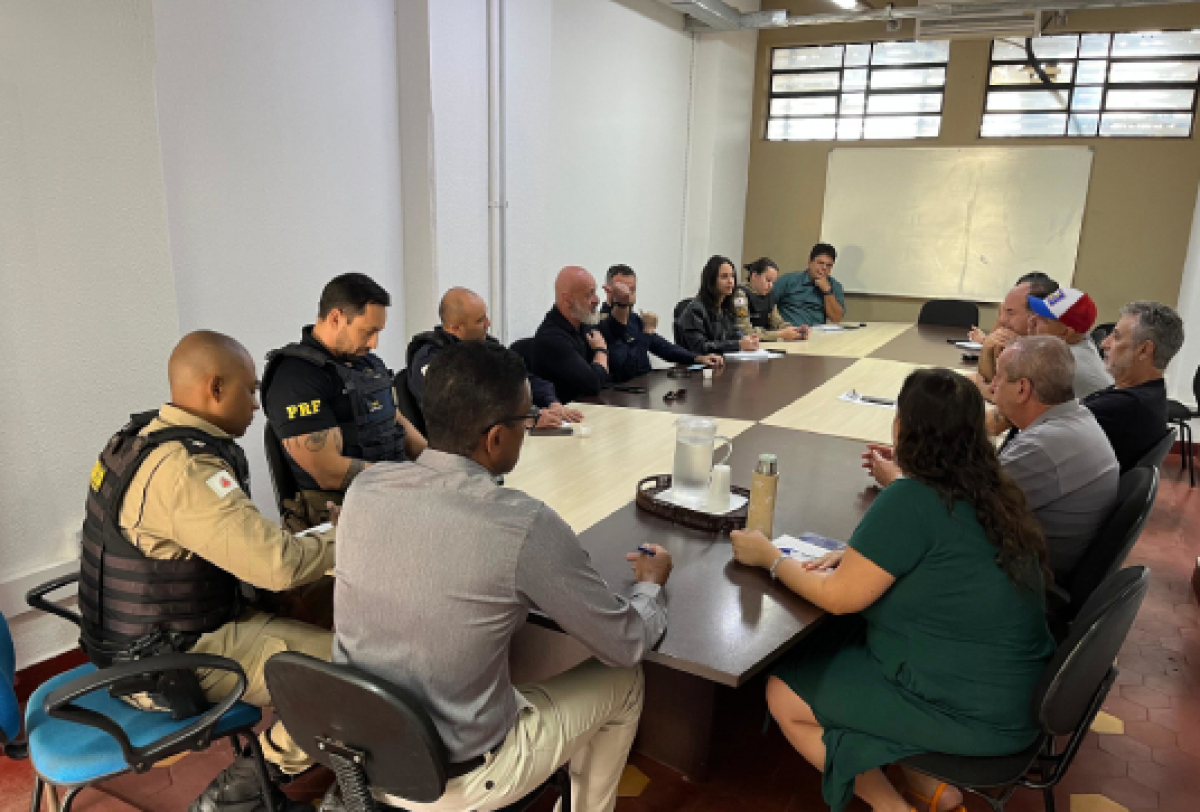 Reunião com participação de policiais e civis discutindo assuntos em uma sala de conferência.