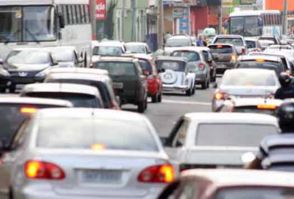 Imagem mostra congestionamento intenso em uma rua urbana de Uberaba, com muitos carros e ônibus.