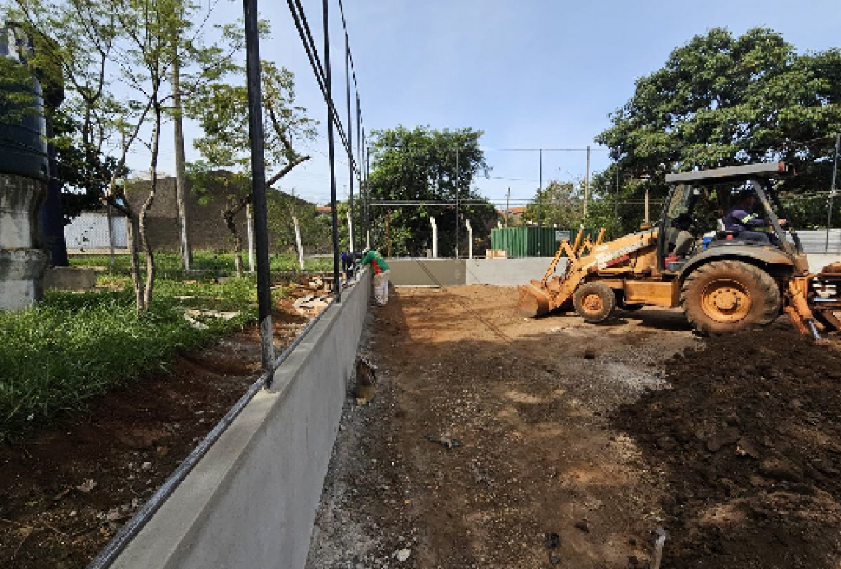 Imagem mostra obras em andamento com trator e operários trabalhando na construção ou reforma de um espaço urbano.