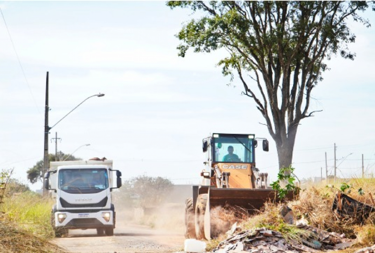 Serviços de limpeza e manutenção urbana com uso de máquina e caminhão em via pública.